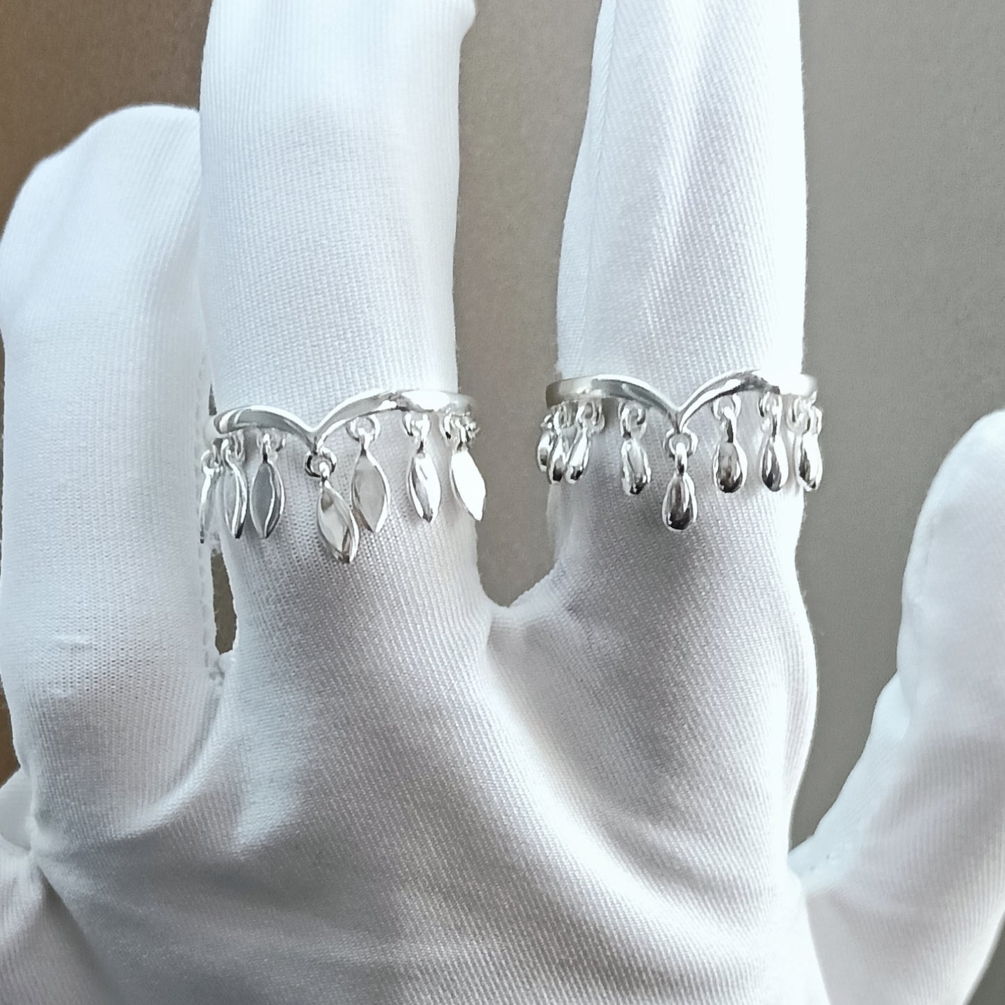 Silver ring with dangling elements on a white glove